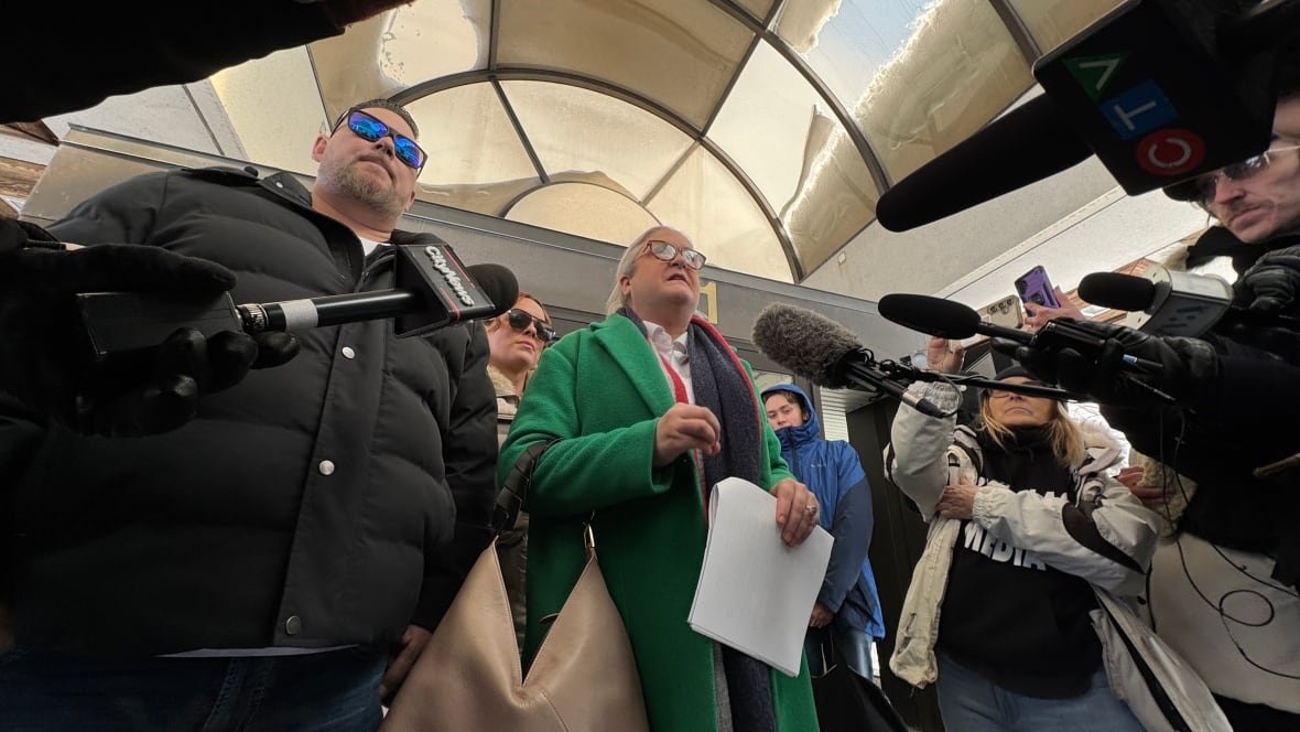 natasha-calvinho-pat-king-sentencing-ottawa-2025 A man and woman stand beside each other in winter jackets. Numerous microphones are being pointed at them by reporters off-screen.