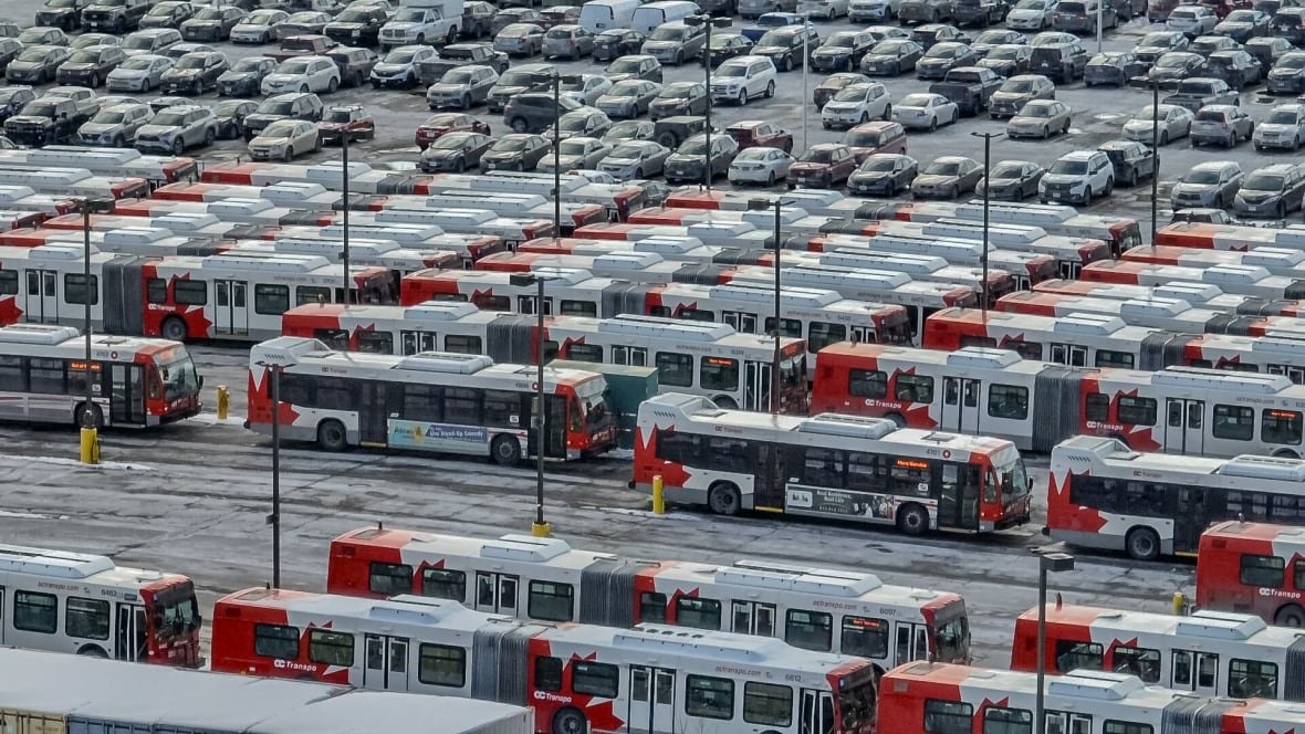 oc-transpo-bus-hq-drone-vis-ottawa A photo of dozens of public buses, all parked in a lot in rows.