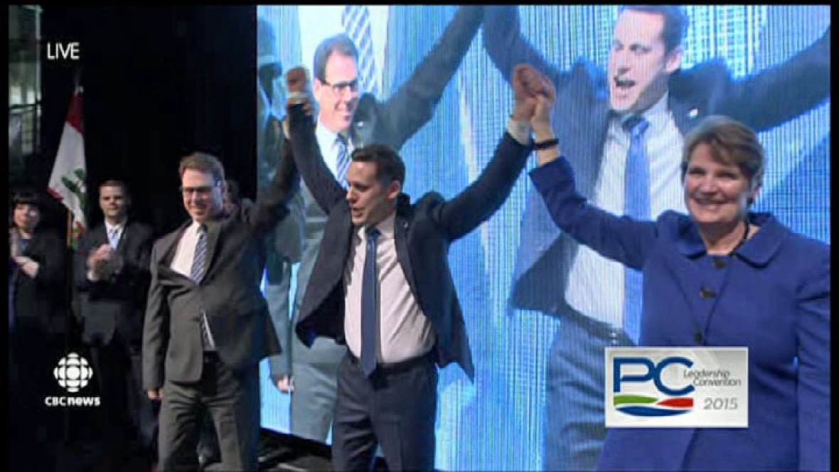 rob-lantz-victory Two men and one woman standing on a stage raising their arms in victory.
