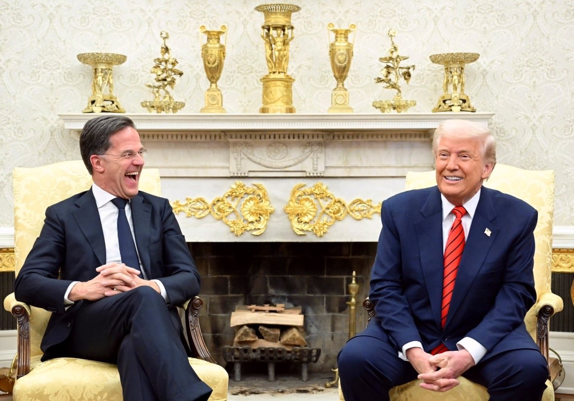 trump-2 Two men sit on chairs in an ornate room.