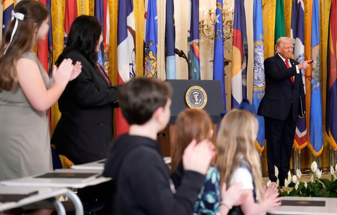trump-3 Donald Trump points as children in the foreground stand and applaud.