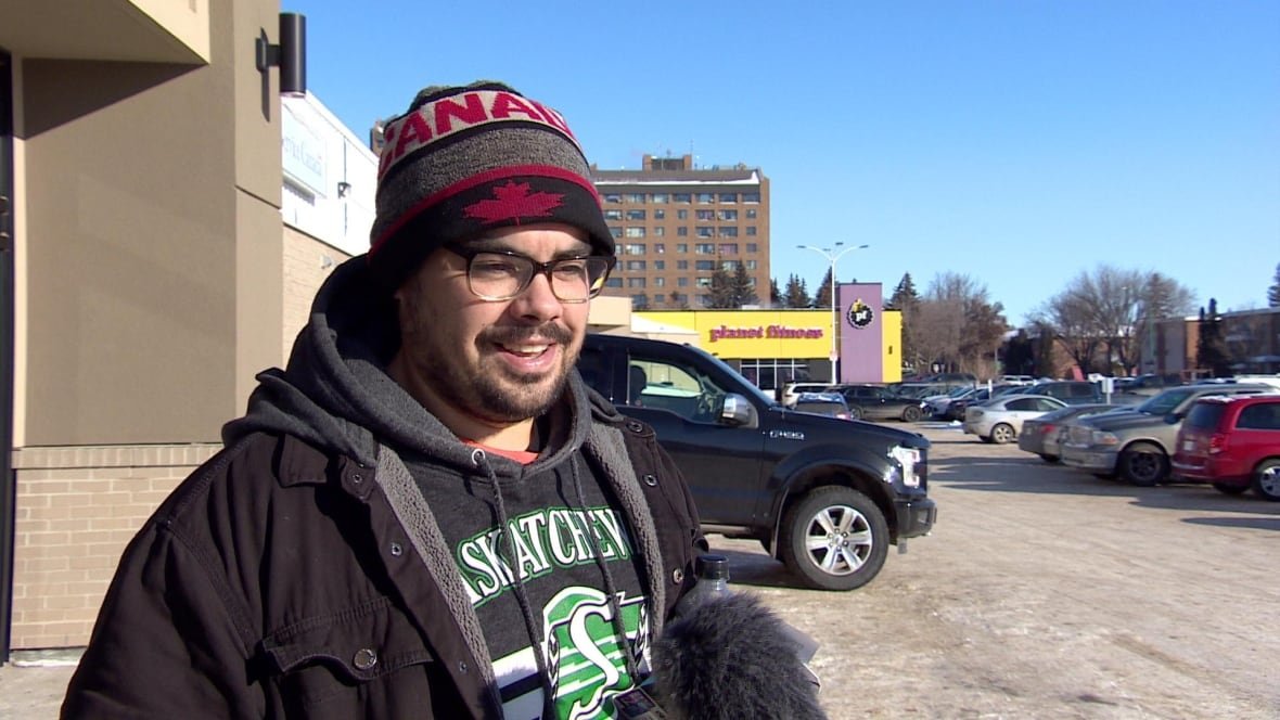 Man in Canadian hat and Saskatchewan shirt stands outside a mall