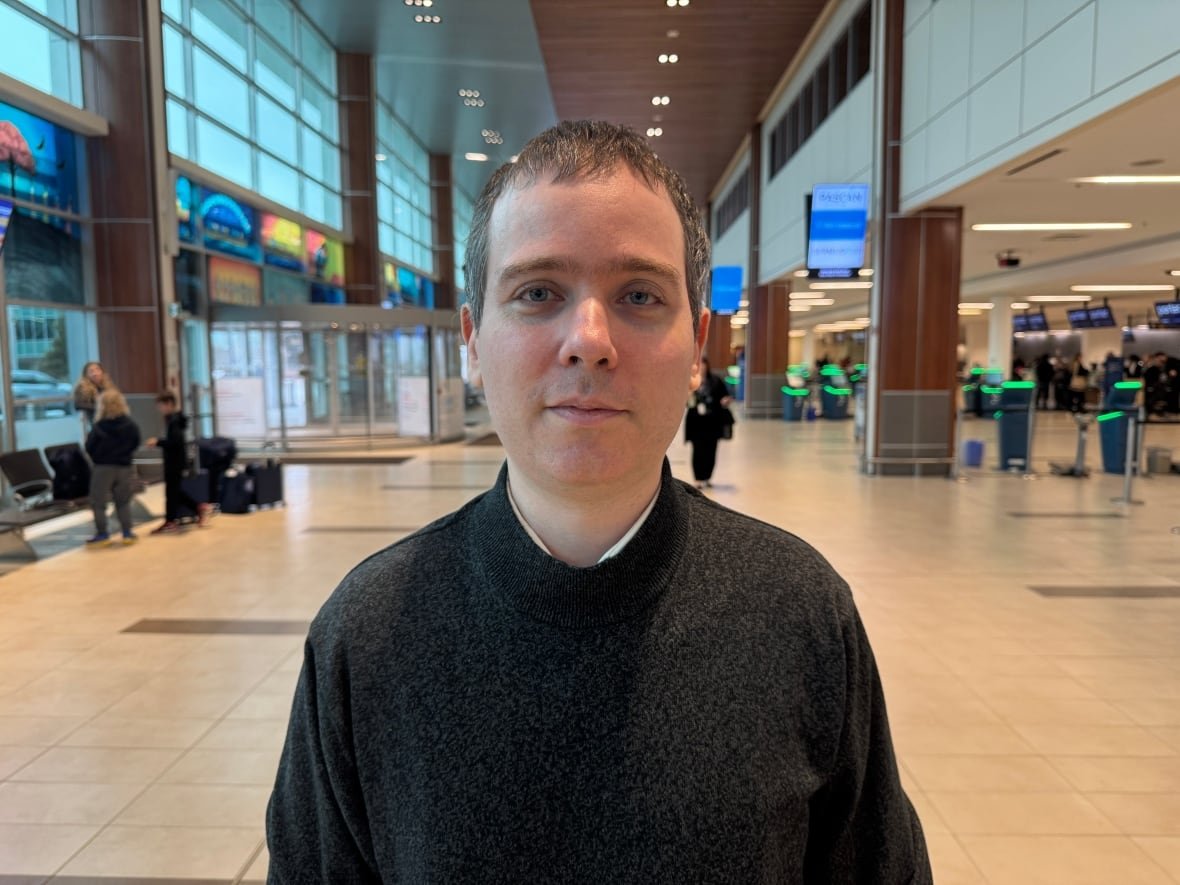 gabor-lukacs-1 Headshot of man standing inside airport terminal looking at camera.