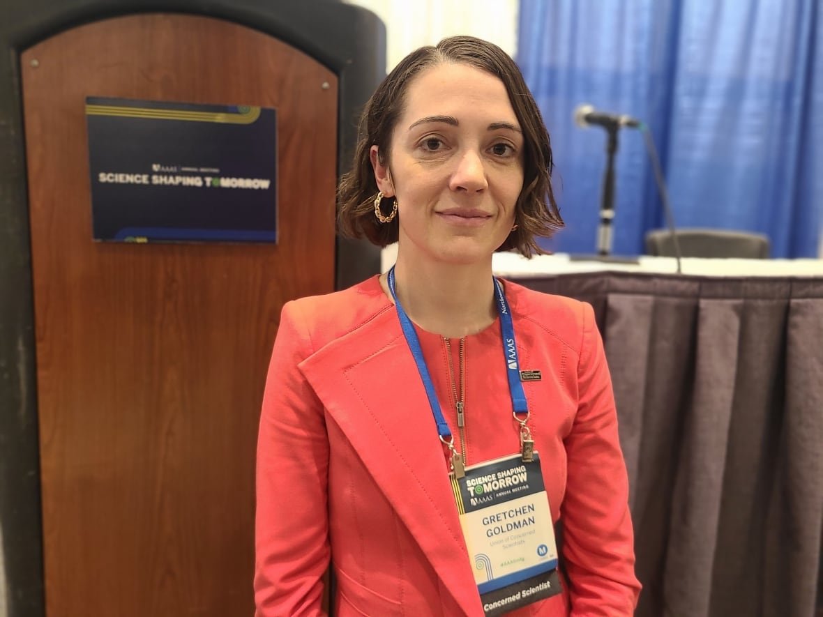 gretchen-goldman-1 Woman with conference badge around neck and microphone in background