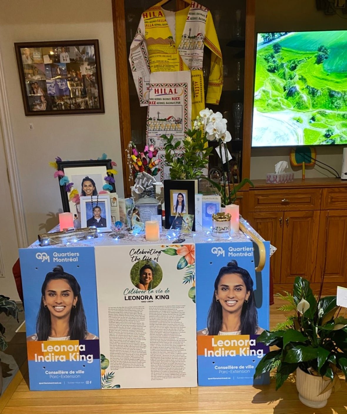 leonora-king-altar A table with Leonora's framed pictures. Larger pictures from her municipal campaign hang on the front. A dress she made out of rice and flour bags hangs behind the table.