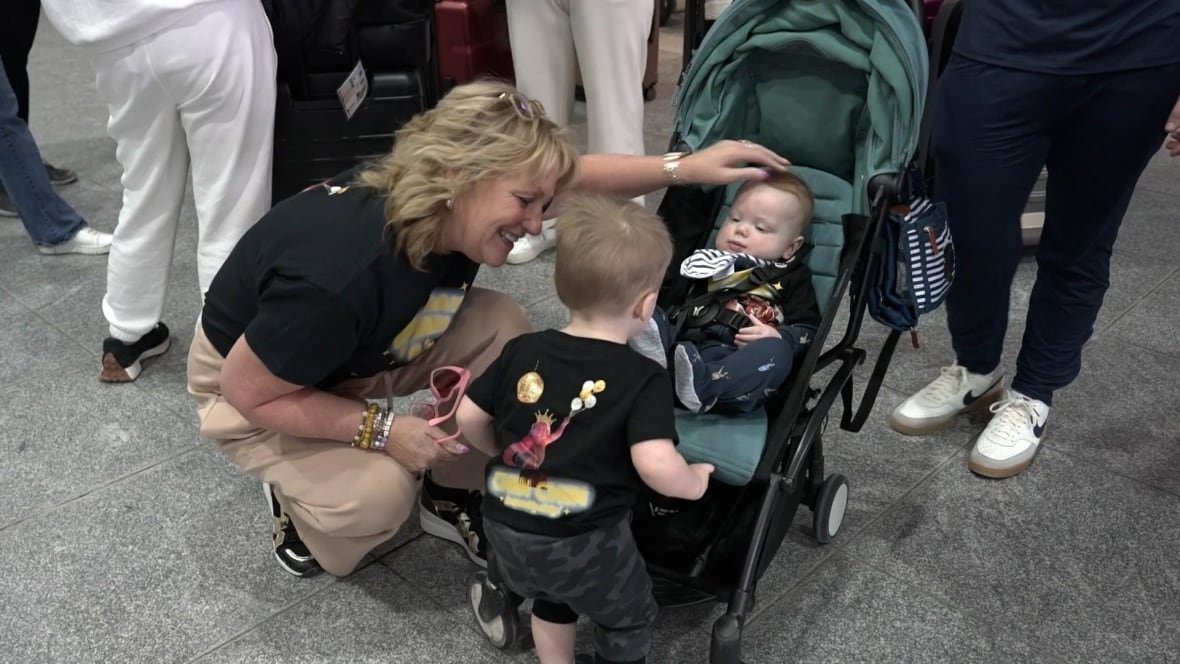 manon-fortin-sunwing A woman crouches over two children in an airport