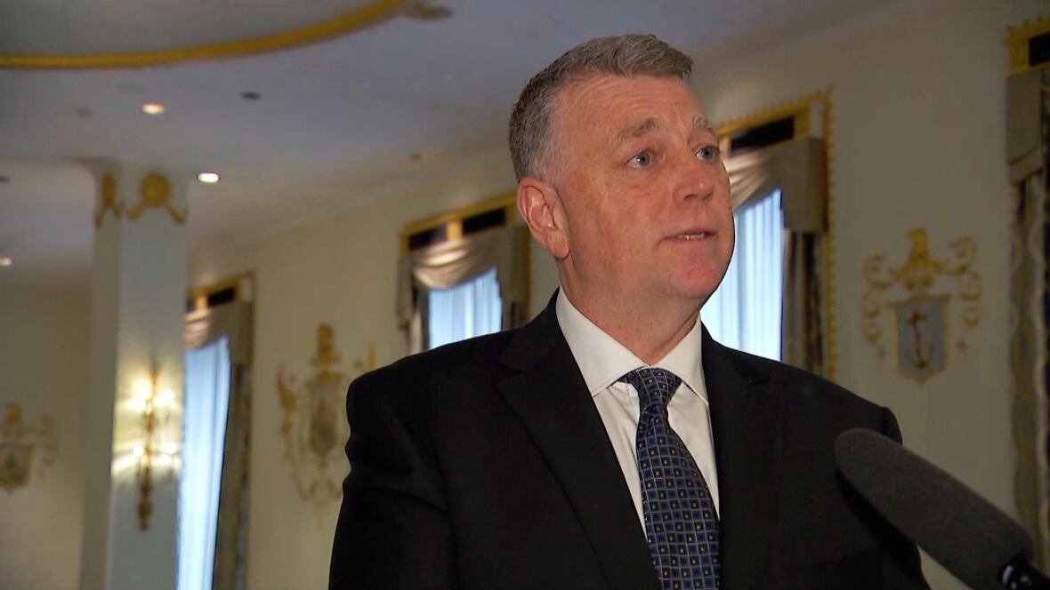 p-e-i-premier-dennis-king A man in a suit speaks into a microphone. He is not looking at the camera.