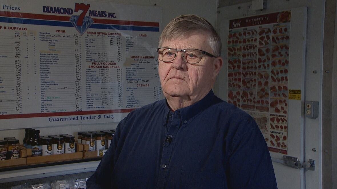 robert-lundquist A man wearing glasses and a blue shirt stands in a room.