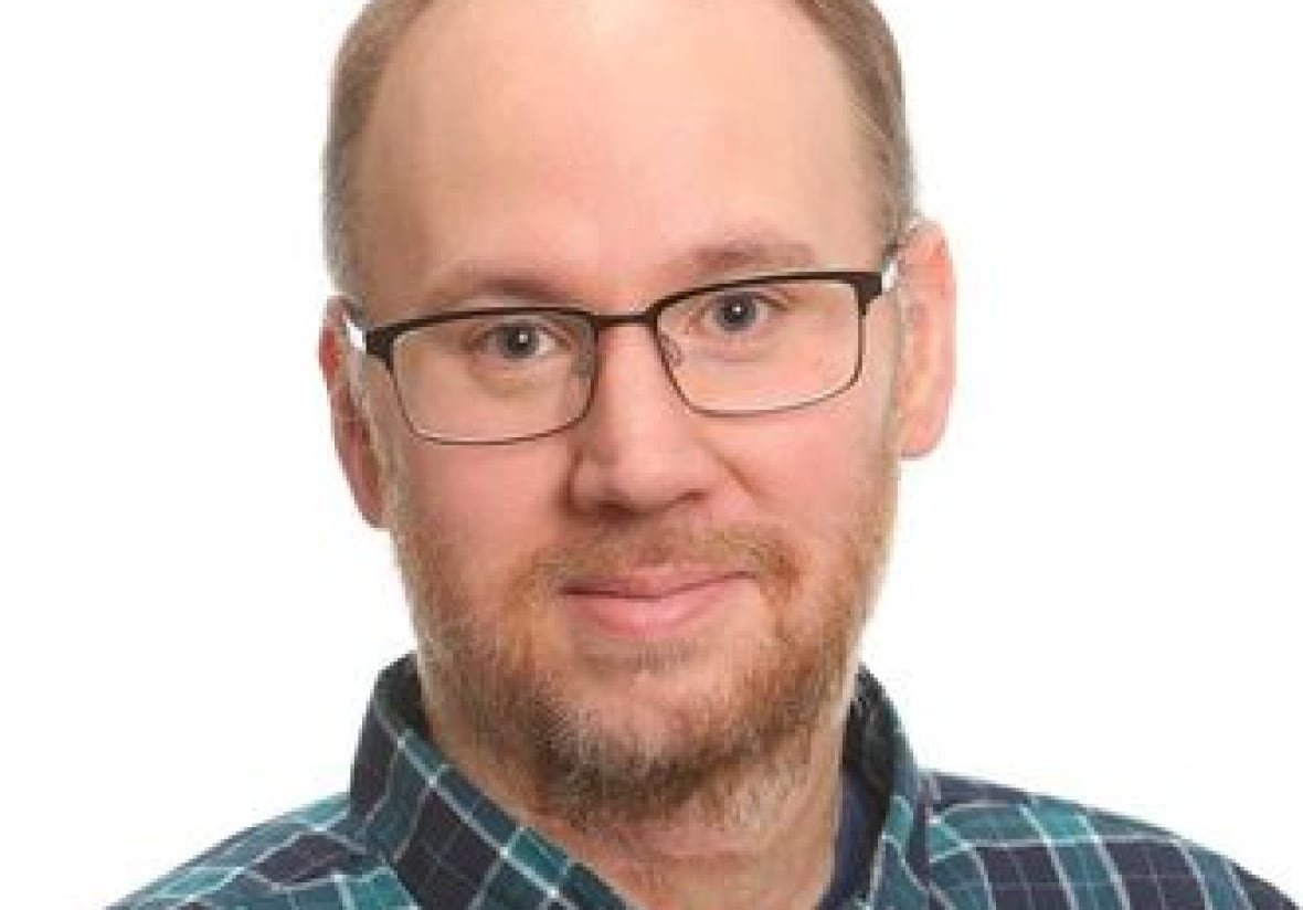 scott-pruysers A headshot of a man in a plaid shirt.