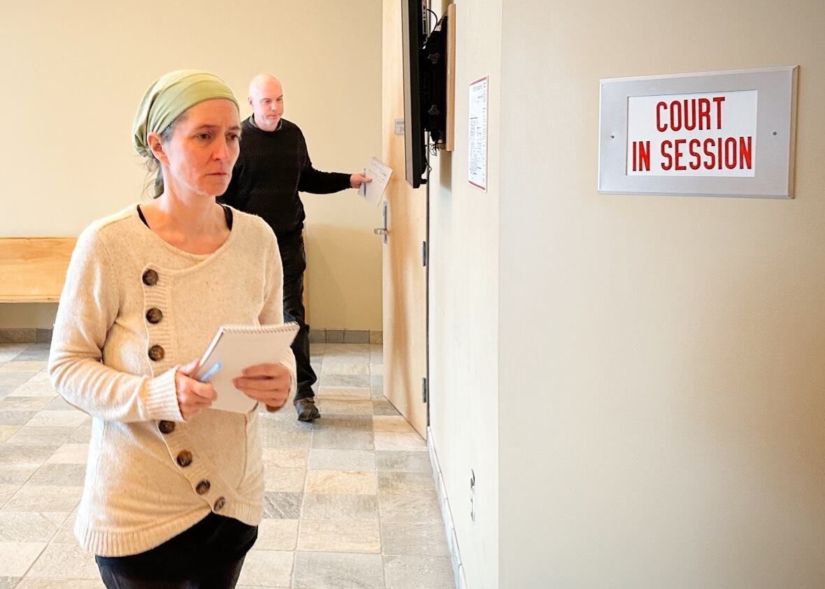 A man and a woman stand in a courtroom corridor.