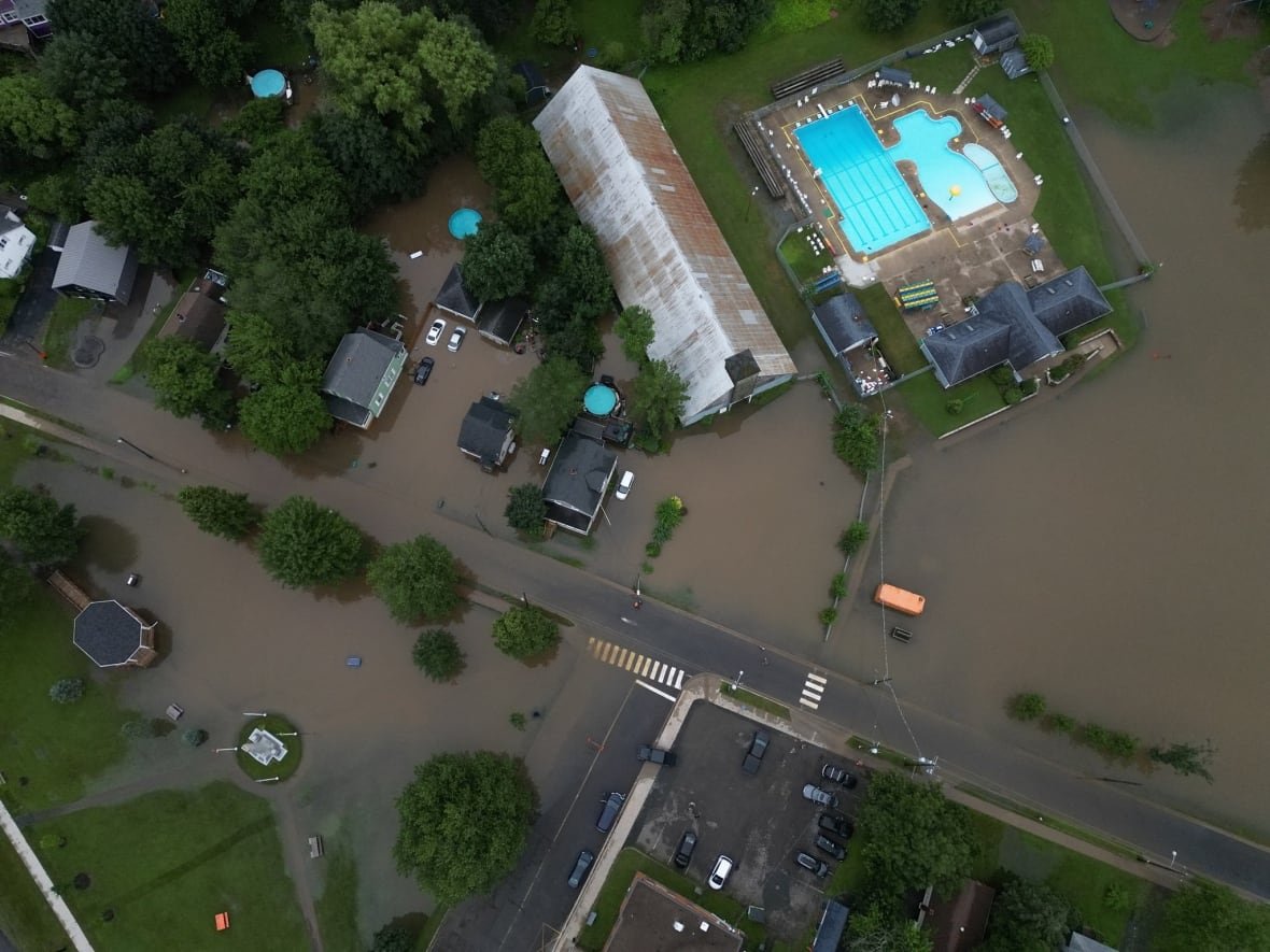 stannus-street-flooding A drone shot shows brown water overflowing into the streets and lawns of a residential area. there's a bright blue swimming pool.