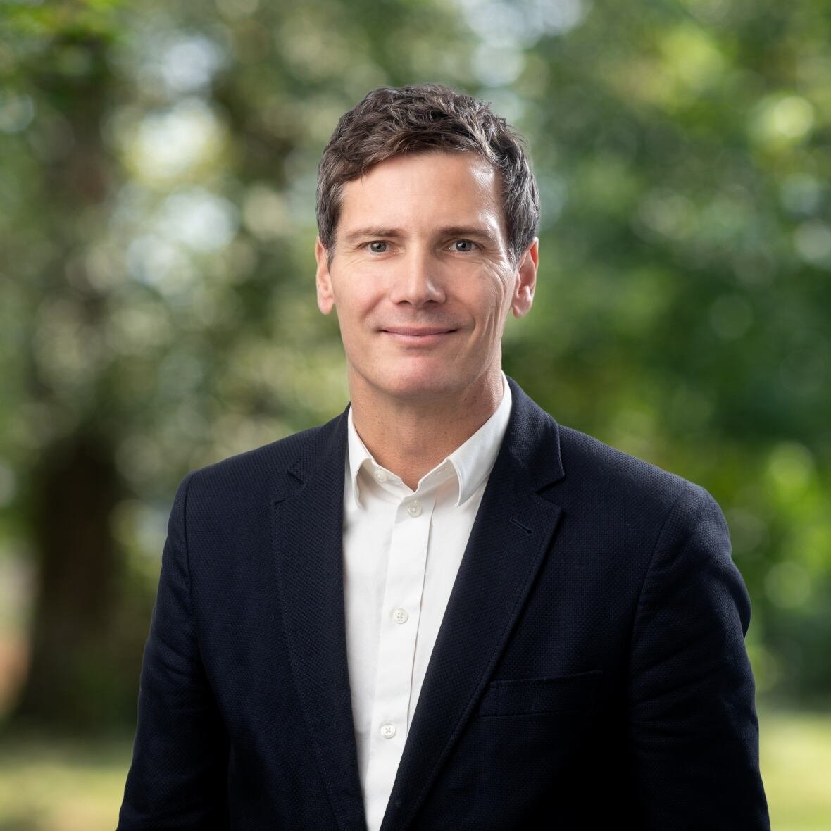 A professional headshot of a man in a suit.
