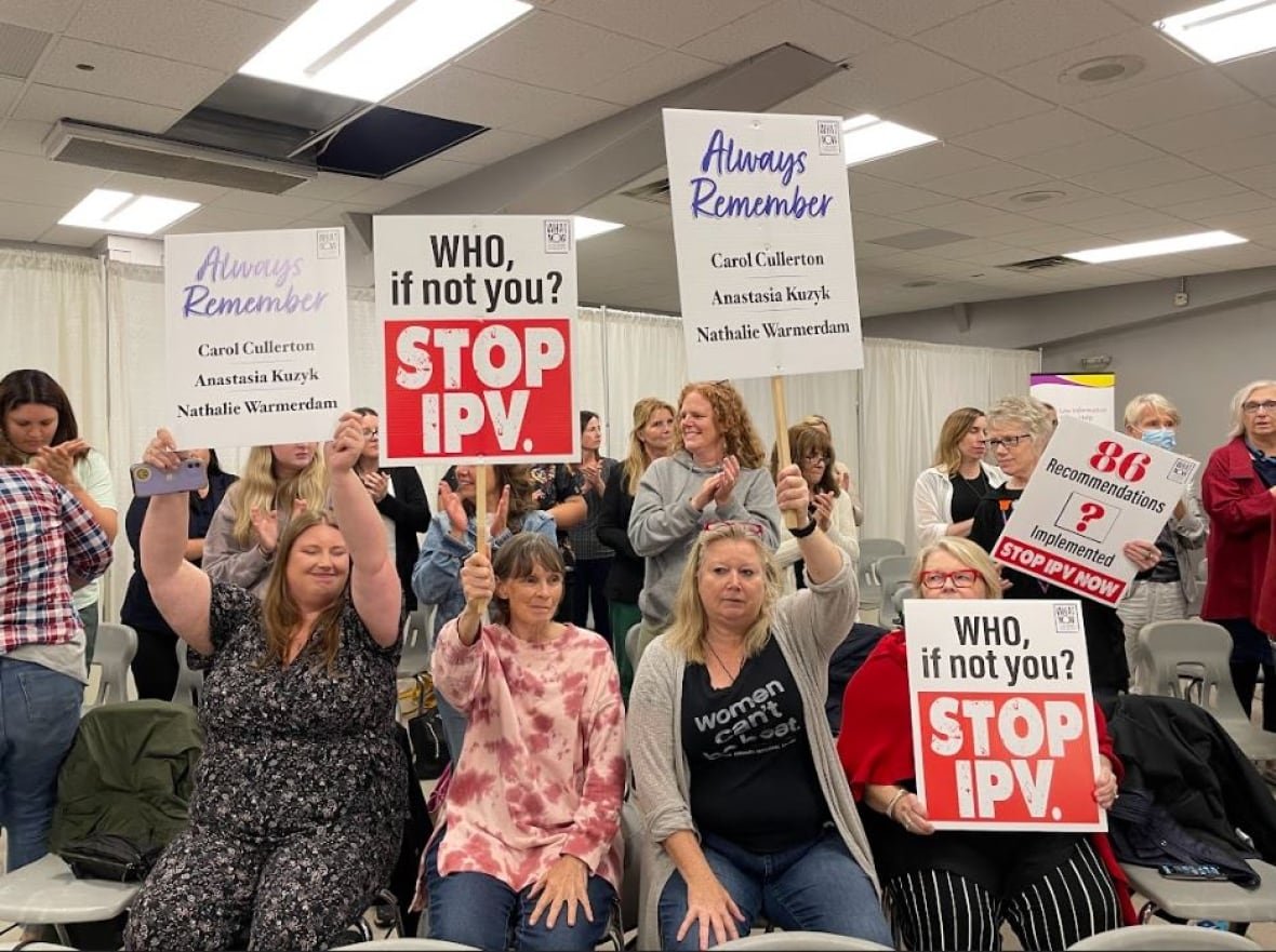 civic-centre-ipv-inquest People hold signs in a meeting room that remember victims of intimate partner violence.