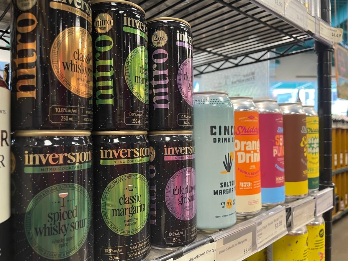 ready-to-drink-cans cans sit on a metal shelf in a liquor store