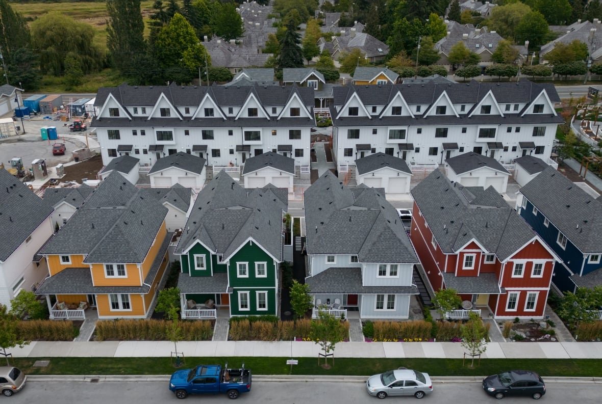 housing-20240812 A row of houses with colorful fronts is shown from an aerial view.