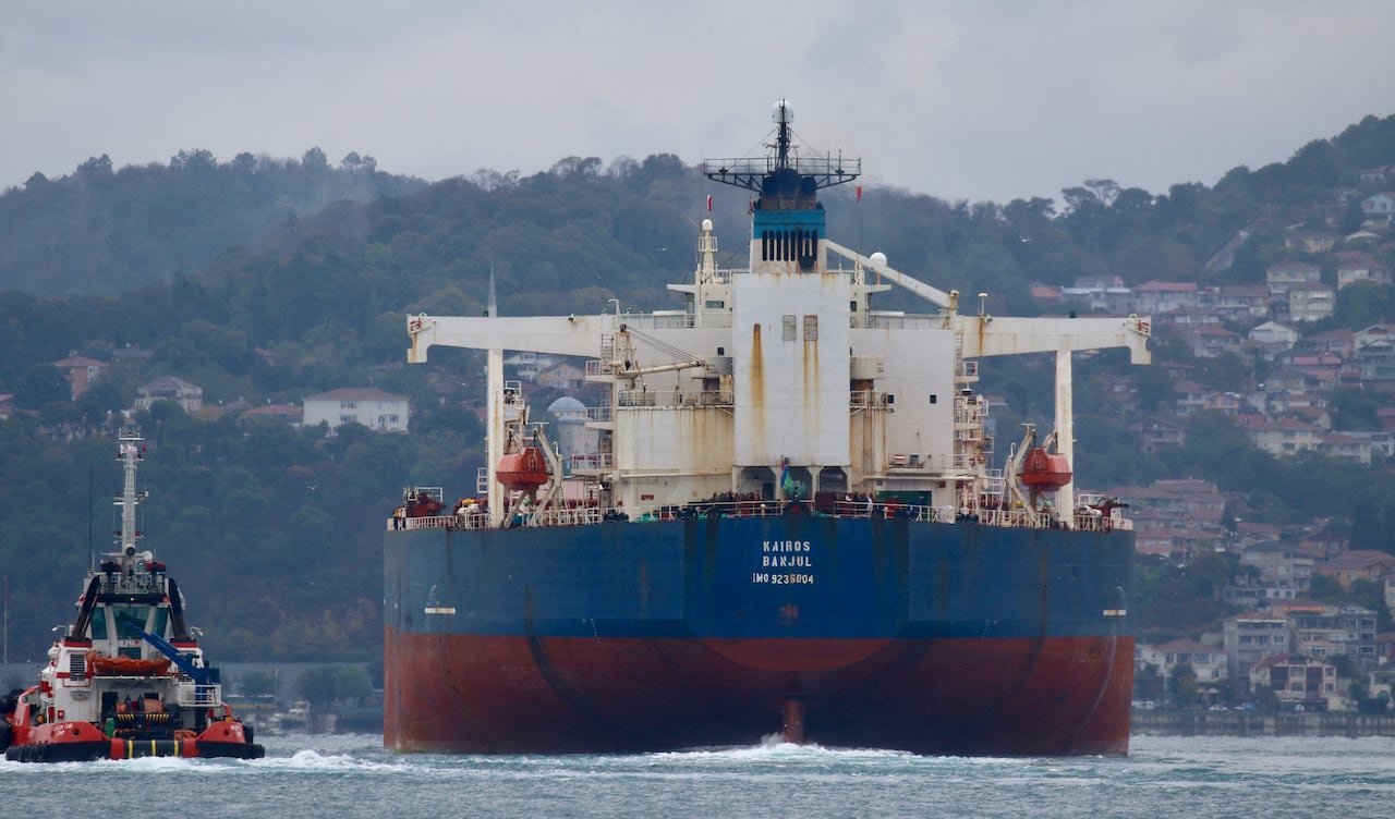Kairos, an oil tanker, is shown in the water beside a smaller boat.