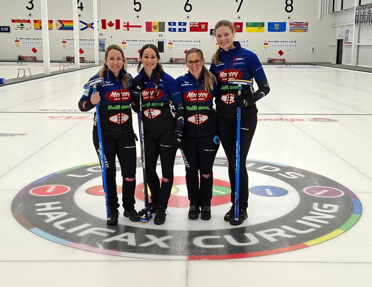 Four women curlers wearing matching outfits pose for a group photo.