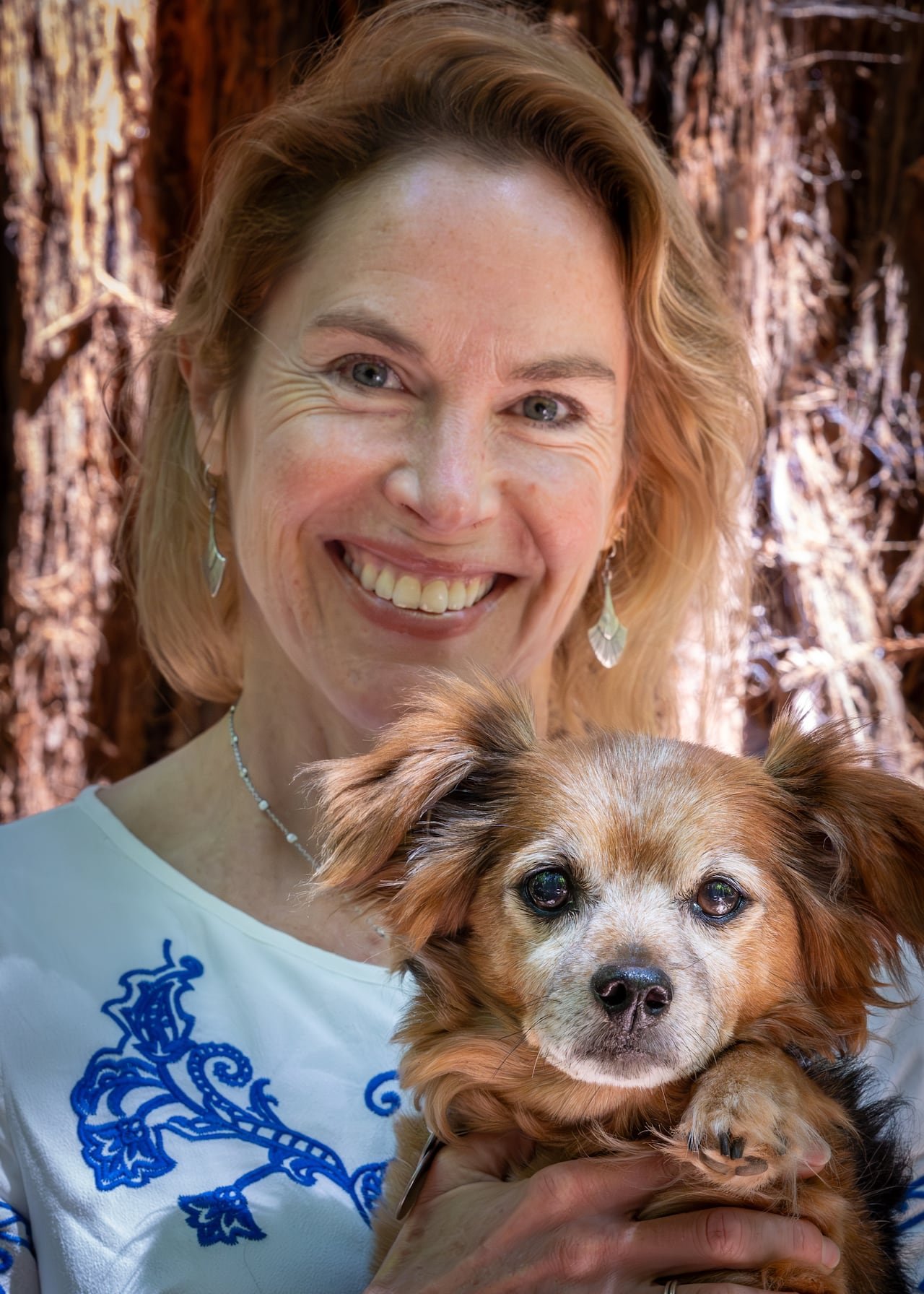 A woman holds a small dog.