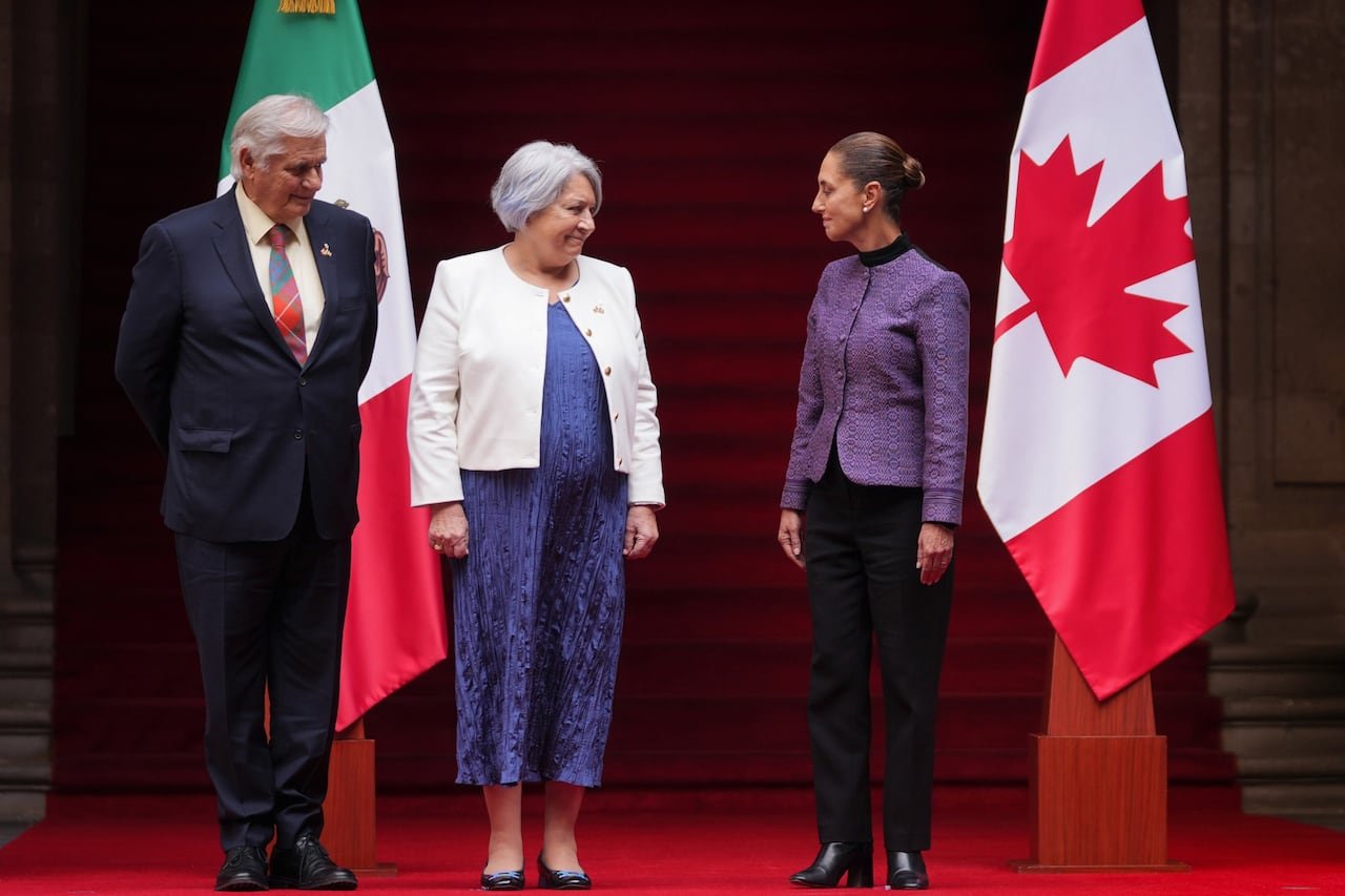 default-643 A man and two women stand next to the flags of Canada and Mexico.