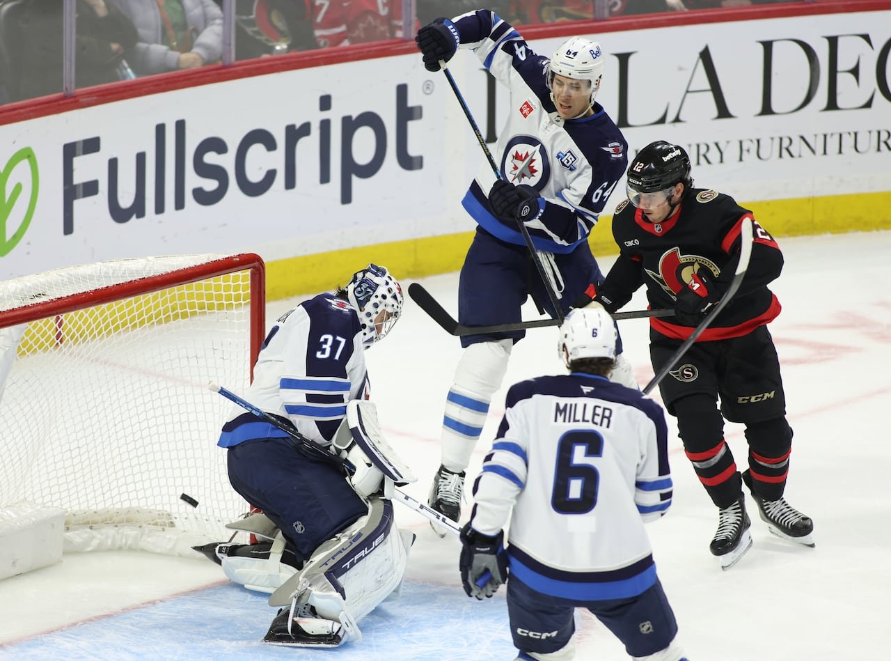 default-331 Four hockey players converging near the net as a puck flies into it.