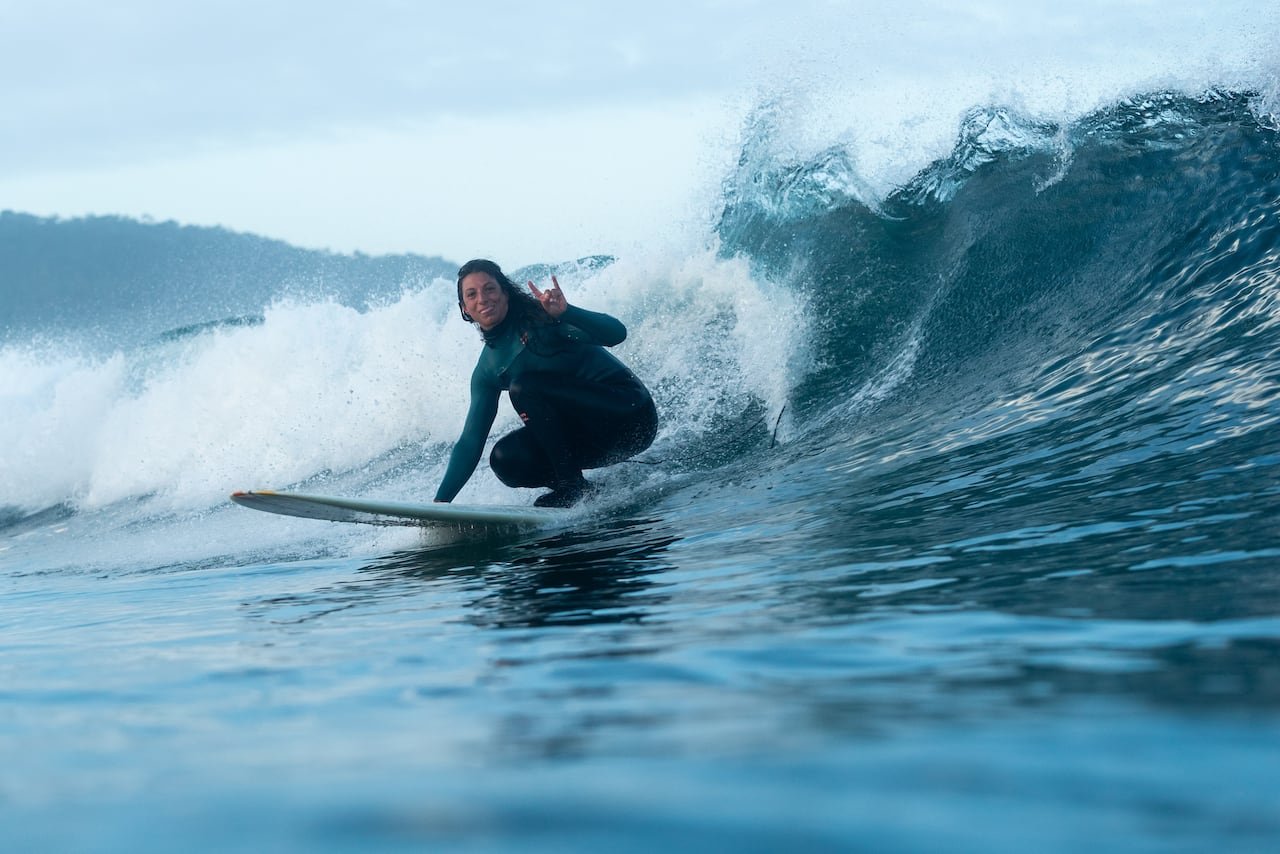 default-349 A woman surfing in the winter looks at the camera as she surfs by.