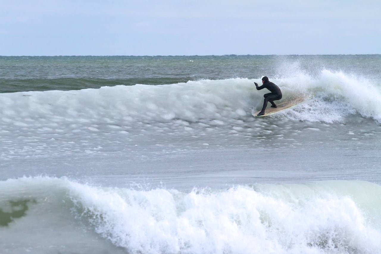 default-350 A man in a wetsuit surfs a wave in the winter.