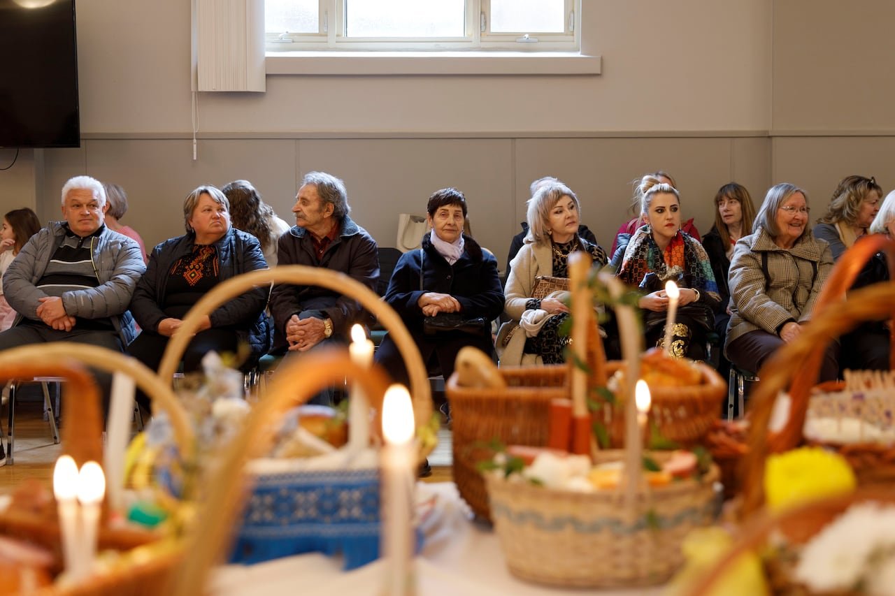 default-229 People in winter clothes sitting in chairs by a table with food baskets.